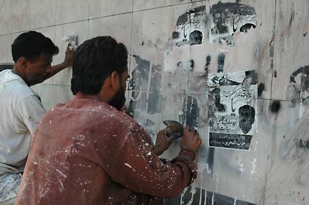 KARACHI/PAKISTAN_ Tow male removing  and washing manual with hands  Graffiti and removing paper posters from the Postguard Narcotic police building   23 Oct. 2012         のeditorial素材