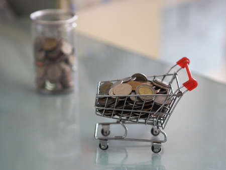 mini model cart type in the supermarket and Many coins are in clear plastic cans out of focus backgroundの写真素材