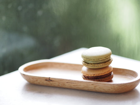 Macaron flavor green tea and coffee in wooden tray plate shape ellipse, Dessert snacks Afternoon on marble table blurred of nature background, Dessert snacks, sweet foodの写真素材