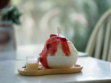 shaved ice with Strawberry syrup and milk, cup of sweet ice. Cool food Dessert in white bowl on wooden trayの写真素材