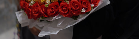 panoramic shot of florist holding bouquet of red roses