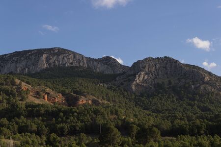 Great rocky mountain with pine trees an afternoon of clouds in the province of Granadaの写真素材