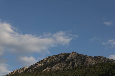 Great rocky mountain with pine trees an afternoon of clouds in the province of Granadaの写真素材