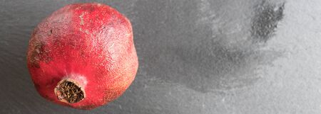 Group of one whole four pieces of fresh red pomegranate on grey stoneの写真素材