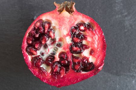ripe red pomegranate and grain on a gray stone backgroundの写真素材