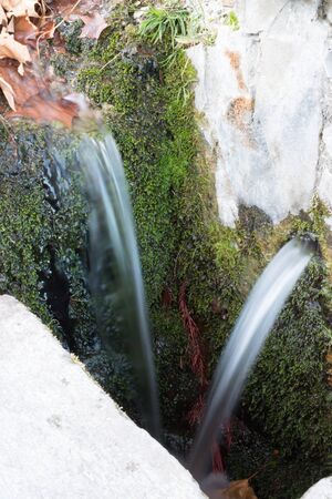 spring of natural water with moss bottom and water with silk effectの写真素材