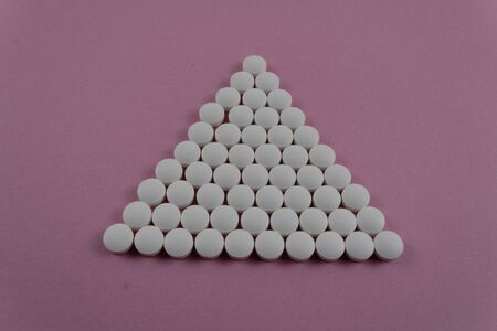 set of tablets with pink background in a pyramidal shape. photography of medicinal productsの写真素材