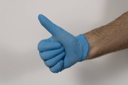 man's hand with latex glove with thumb upの写真素材