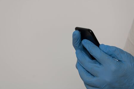 hands protected with nitrile gloves holding a mobile phoneの写真素材