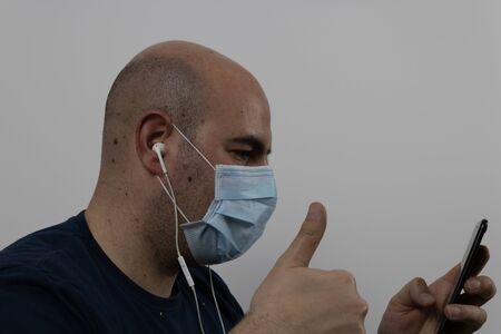 bald man in a mask making a video call with headphonesの写真素材