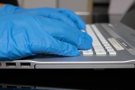 Gloved hands typing on computer keyboardの写真素材