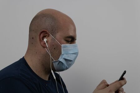 Man in mask texting with cell phoneの写真素材