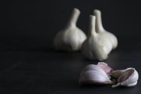 garlic cloves and unfocused garlic heads on a black background. dark foodの写真素材