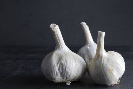 three heads of garlic grouped on the right side on a black background. dark foodの写真素材