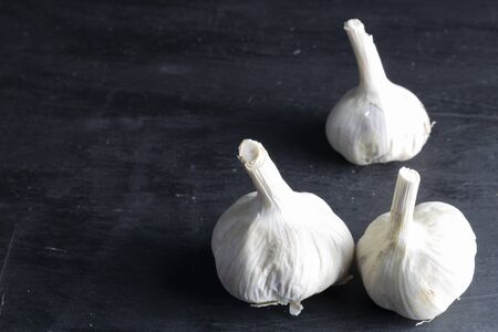 three heads of garlic located on the right side with black background. dark foodの写真素材
