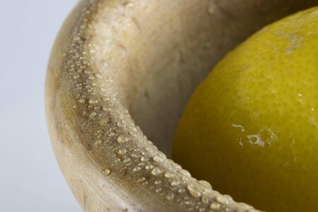 fresh lemon in a wooden bowl placed on the right, isolated on a white backgroundの写真素材