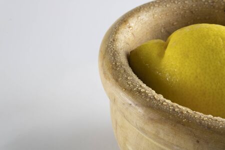 fresh lemon in a wooden bowl placed on the right, isolated on a white backgroundの写真素材