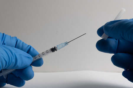 nurse with blue latex gloves uncovering needle syringeの写真素材