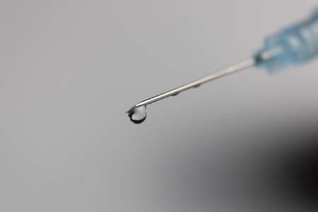 syringe needle with a drop of medicine at the tip, checking for airの写真素材