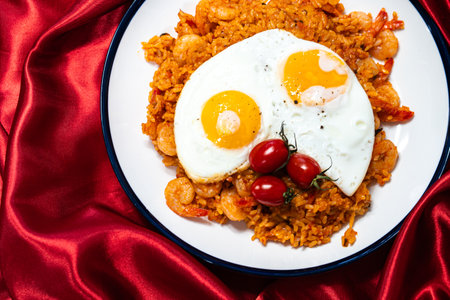 Fried rice with shrimps, tomatoes and fried egg on a white plate.の写真素材