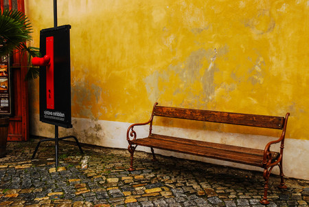 Empty wooden bench with yellow wallの写真素材