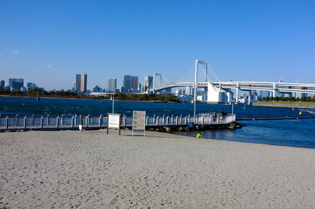 empty beach scene of odaiba island, tokyo, japan entirely made of gabage with rainbow bridge and clear sky in backgroundの写真素材