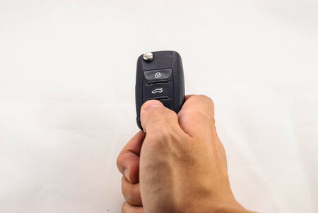 human hand pushing unlock button of car key isolated in white backgroundの写真素材