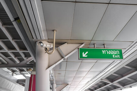 exit sign with security camera in train station