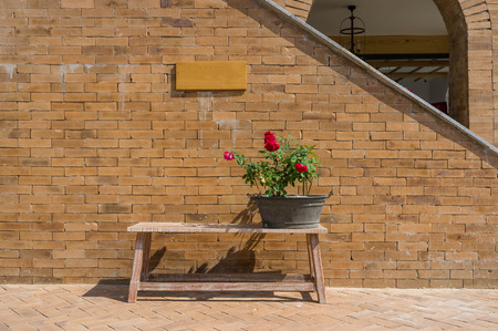 old public bench with bouquet of flower and brick wall