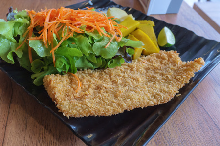 fried fish and salad green served in restaurantの写真素材