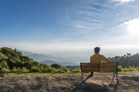 Traveler man siting wooden bench with Mountains background ,Doi Inthanon Thailand,の写真素材