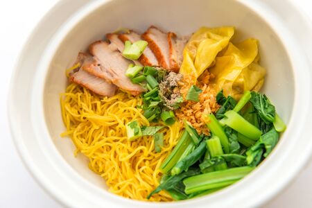 Chinese egg noodle with barbecue pork and dumpling on bowl on white backgroundの写真素材