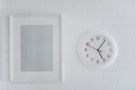 White modern picture frame white and modern analog clock on a brick wall backgroundの写真素材