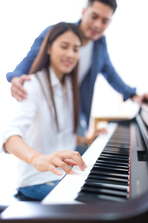husband teaching his wife to play the piano, concept for family relationshipの写真素材
