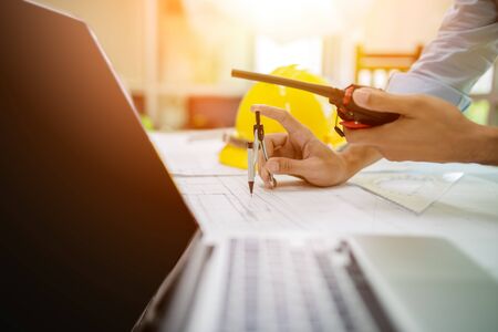 architect man working with laptop and blueprints,engineer inspection in workplace ,sketching a construction project ,selective focusの写真素材