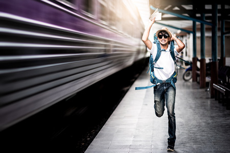Traveler man running after a moving train from a railway stationの写真素材