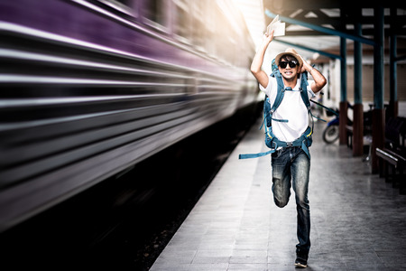 Traveler man running after a moving train from a railway stationの素材 [FY310106238466]