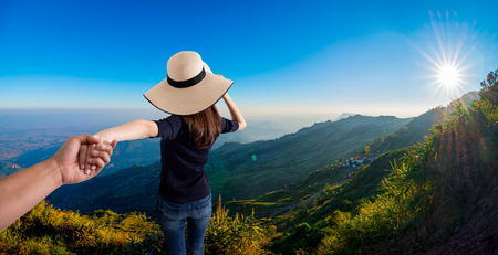 woman holding hand of her husband while running together on the Mountain , holiday vacation or valentine conceptの写真素材