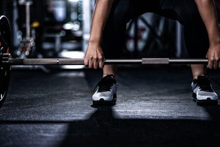 Closeup of young woman holding barbell in the fitness gymの写真素材