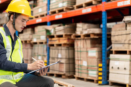 Warehouse worker checking packages on shelf in a large store