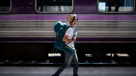 Traveler waits train at train station for travel in summer. Travel concept.