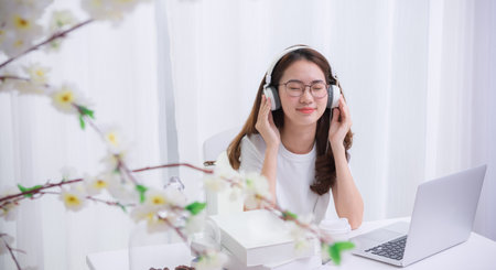 Happy Asian woman relaxing listen to the music connecting the internet with a laptop