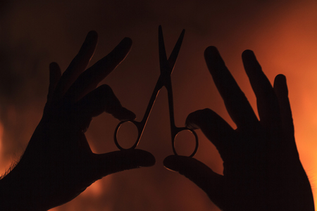 hand holding scissors against a background of fire,Master class haircuts, hair salon, stylish beauty...