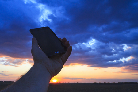 poor mobile connectivity through weather hand with phoneの写真素材