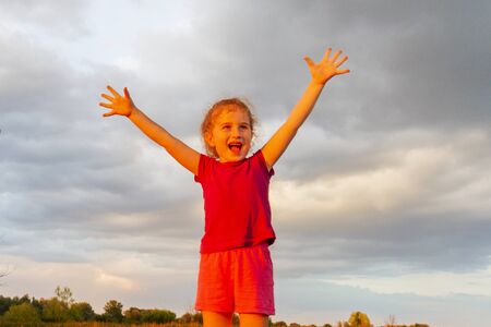 Free little girl with open arms at sunset