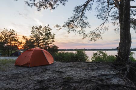 tents stand on the river bank at sunrise, summer restの写真素材