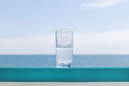 glass of clean cool water against the background of the seaの写真素材