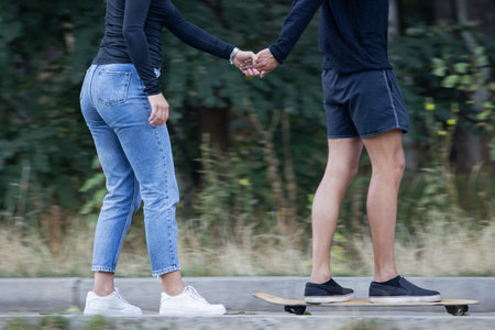couple ride skateboards in a town parkの写真素材