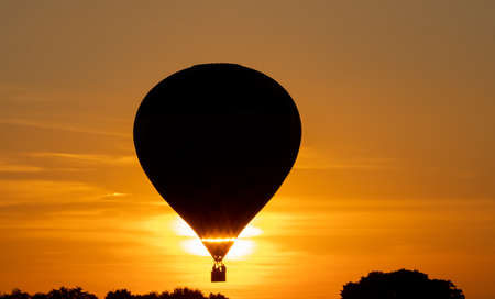 hot air balloon with travelers flying at sunsetの写真素材