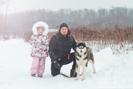 father and daughter walking the dog in winterの写真素材